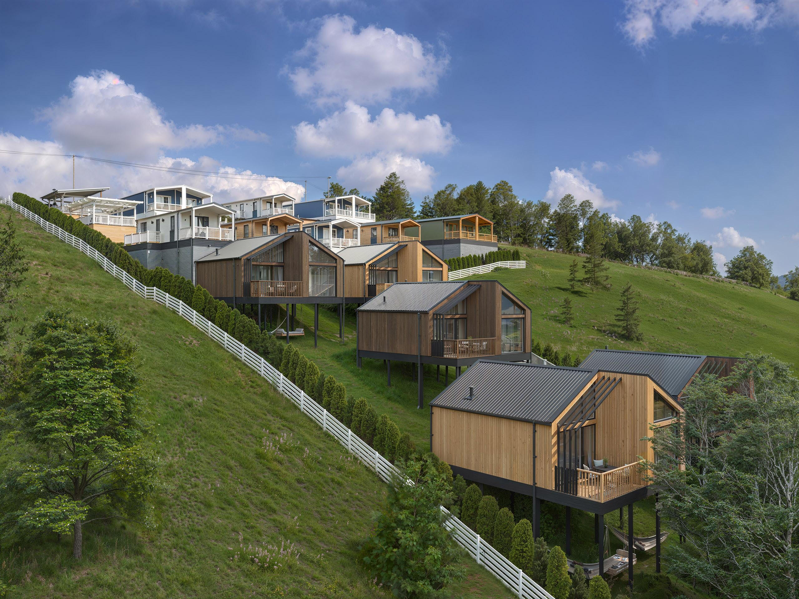 Photorealistic rendering of modern eco-lodges nestled on a hillside. High quality architectural visualization showcasing sustainable design and scenic mountain views.